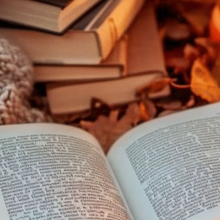 A book with a candle besides it , a fluffy blanket with a stack of books