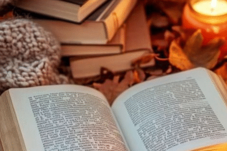 A book with a candle besides it , a fluffy blanket with a stack of books
