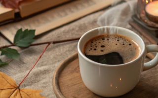 A cup of coffee with autumn leaves and a candle light
