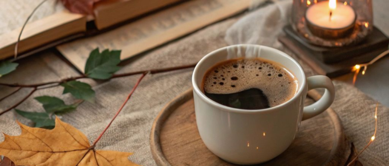 A cup of coffee with autumn leaves and a candle light
